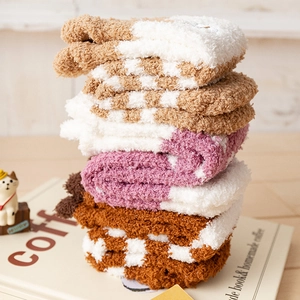 Close-up of stacked fluffy coral fleece socks with checkerboard and striped patterns