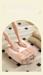 Pink travel compression bag with mesh window and handle showing manual hand pressing detail
