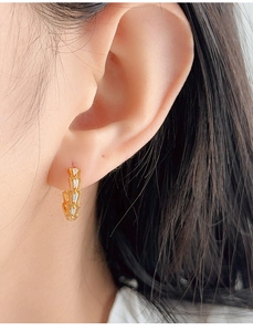Macro detail of gold-plated scale earrings with sparkling white cubic zirconia stones