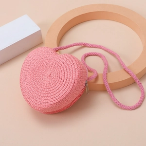 Detailed close-up of pink heart-shaped straw woven mini bag with delicate texture
