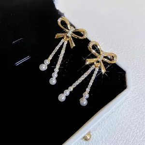 Elegant gold-plated bow pearl tassel earrings with zircons on black jewelry box