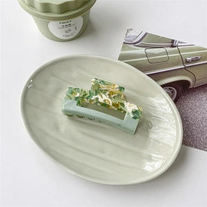 Detail of green and white marble acetate hair claw clip on a light green tray