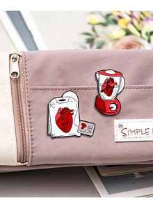 Detailaufnahme von Cartoon-Herz-Emaille-Pins an einer lila Segeltuchtasche