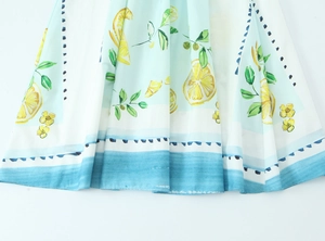 Detailed close-up of summer poplin dress with vibrant yellow lemon and blue floral prints