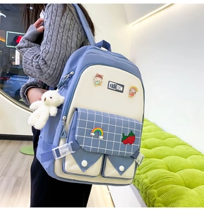 Blue and white school backpack detail with cartoon badges and a plush bear pendant