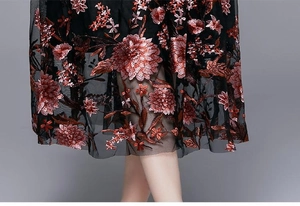 Detailed close-up of intricate red floral embroidery on black mesh tulle dress fabric
