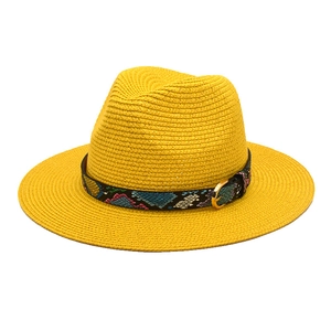 Detail of yellow straw fedora hat featuring a colorful snakeskin band and gold metal buckle