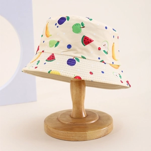Detail of a beige kid's bucket hat featuring vibrant hand-painted fruit patterns and cotton fabric