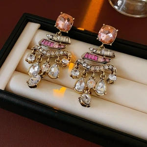 Detail of vintage gold earrings with pink gemstones and crystal tassels on velvet padding