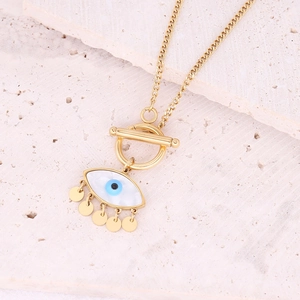 Golden evil eye necklace with mother of pearl inlay and five dangling charms on a stone background