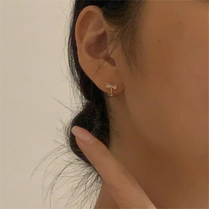 Close-up of elegant gold bow earrings with white cubic zirconia worn by a model