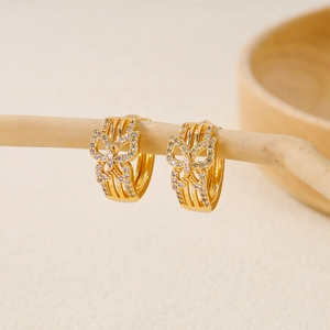 Detail shot of gold-plated butterfly hoop earrings with white zircon on a branch