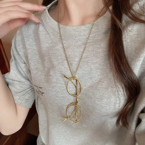Detail view of a long gold chain necklace with a vintage round glasses shaped pendant