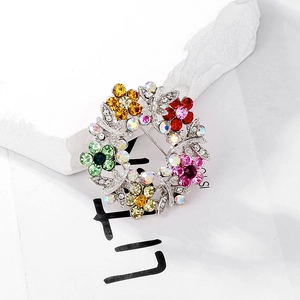 Exquisite silver-tone floral wreath brooch with colorful rhinestones on white stone base