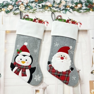 Detail of felt Christmas stockings with 3D Santa and Penguin embroidery by fireplace