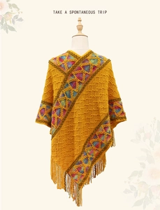 Detail of yellow knit poncho with colorful geometric ethnic patterns and fringe trim