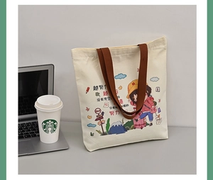 Detail of canvas tote bag featuring cartoon girl illustration and sturdy brown strap