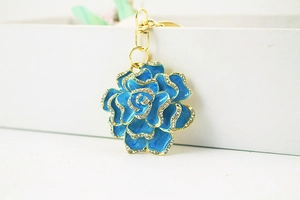 Detail of blue rhinestone rose keychain with gold metal clasp on white gift box edge