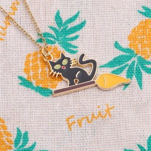 Détail macro du pendentif émaillé chat noir sur balai doré avec chaîne fine