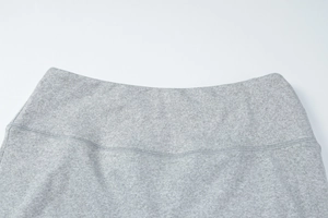 Detailed close-up of grey knit waist stitching and textured blend fabric of a two-piece set