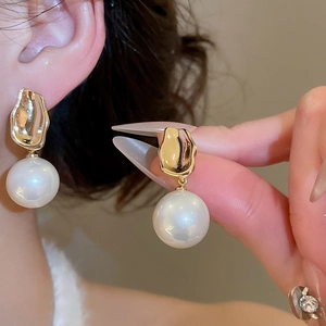 Detail of elegant gold organic metal drop earrings with large round pearls on model