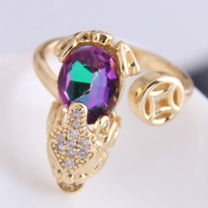 Macro view of gold-tone beast ring featuring a colorful oval gemstone and coin accents