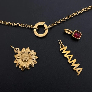 Détail de charms MAMA et tournesol dorés avec une pierre précieuse rouge