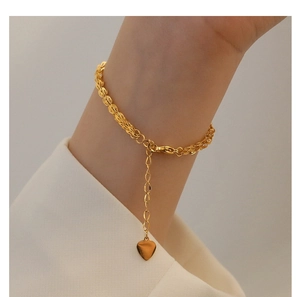 Detailed close-up of a gold-plated titanium woven chain bracelet with a heart pendant