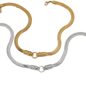 Polished gold and silver snake head pendants with green gemstone eyes on snake bone chains
