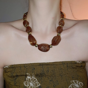 Close-up of irregular reddish-brown glitter beads and gold spacers on acrylic necklace