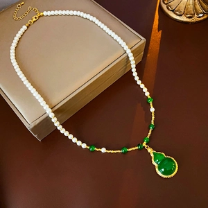 Détail d'un collier plaqué or avec perles blanches et pendentif en jade en forme de gourde