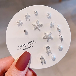 Detail of multi-style silver stud earring set with starfish and cherry charms on a white card