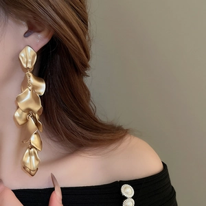 Close-up of matte gold long petal fringe earrings worn by a model in a fashion shot