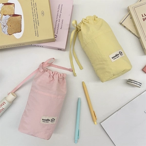 Pink and yellow drawstring stationery pouches in soft nylon with minimalist woven labels