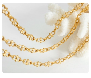 Macro shot of gold-plated chunky link chain jewelry on white coral background