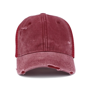 Close-up of distressed cotton baseball cap with mesh back and vintage burgundy finish