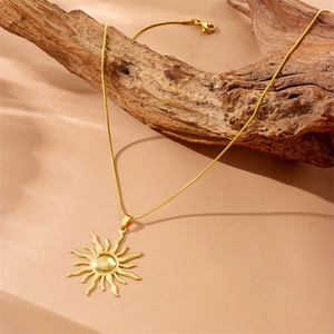 Gold sun totem pendant necklace with snake chain hanging on a weathered wooden branch