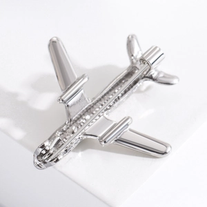 Detail view showing the silver airplane brooch back with a secure pin clasp mechanism