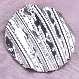 Macro shot of silver 304 stainless steel round pendant with wavy ripple texture details