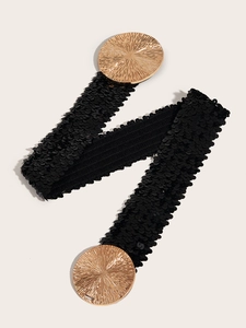 Close-up of black elastic waist belt featuring gold circular metal buckles with texture