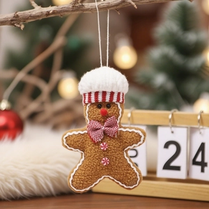 Close-up of a gingerbread man plush ornament hanging on a festive wooden branch