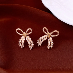 Detail view of gold-plated bow earrings with white cubic zirconia on dark velvet