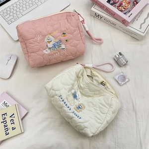 Close-up of quilted makeup bags with heart stitching, cute embroidery, and wristlet handle
