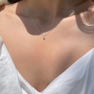 Detail of a 925 silver necklace featuring a sparkling pear-cut zircon pendant on model