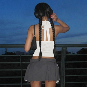 Detail of white backless halter top with a stylish ribbon bow and grey pleated skirt