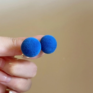 Detail shot of blue flocked spherical stud earrings with a soft velvet texture