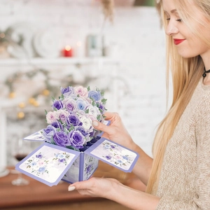 Woman holding an opened 3D pop-up card featuring a bouquet of purple and blue roses
