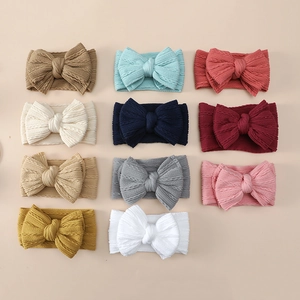 Flat lay of soft cable knit baby headbands with double-layer bows in eleven various colors