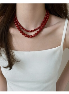 Gros plan sur un collier double rang en perles de verre rouges style rétro français