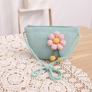 Détail du sac bandoulière tressé vert menthe avec fleur rose 3D et pompons jaunes